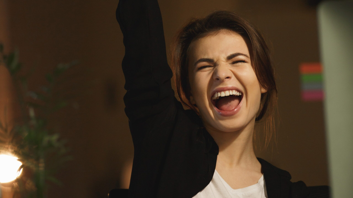 Image of yawning young lady designer sitting in office at night using computer.